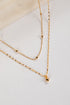 Gold necklace on a light gray surface