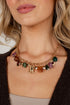 A close-up of a model wearing a gold-toned charm necklace with multiple colorful gemstone drops and a central lock-shaped pendant.