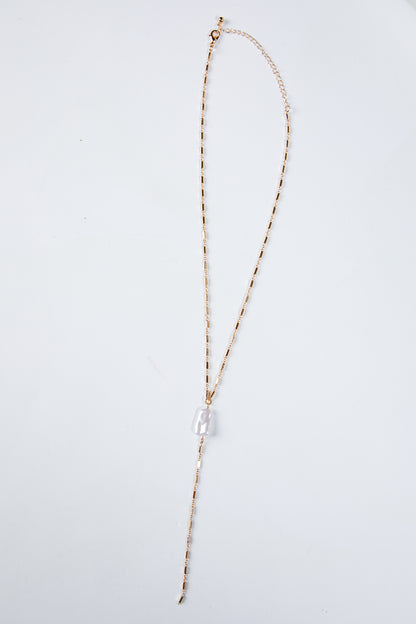 Long necklace with a clear pendant on a light gray background