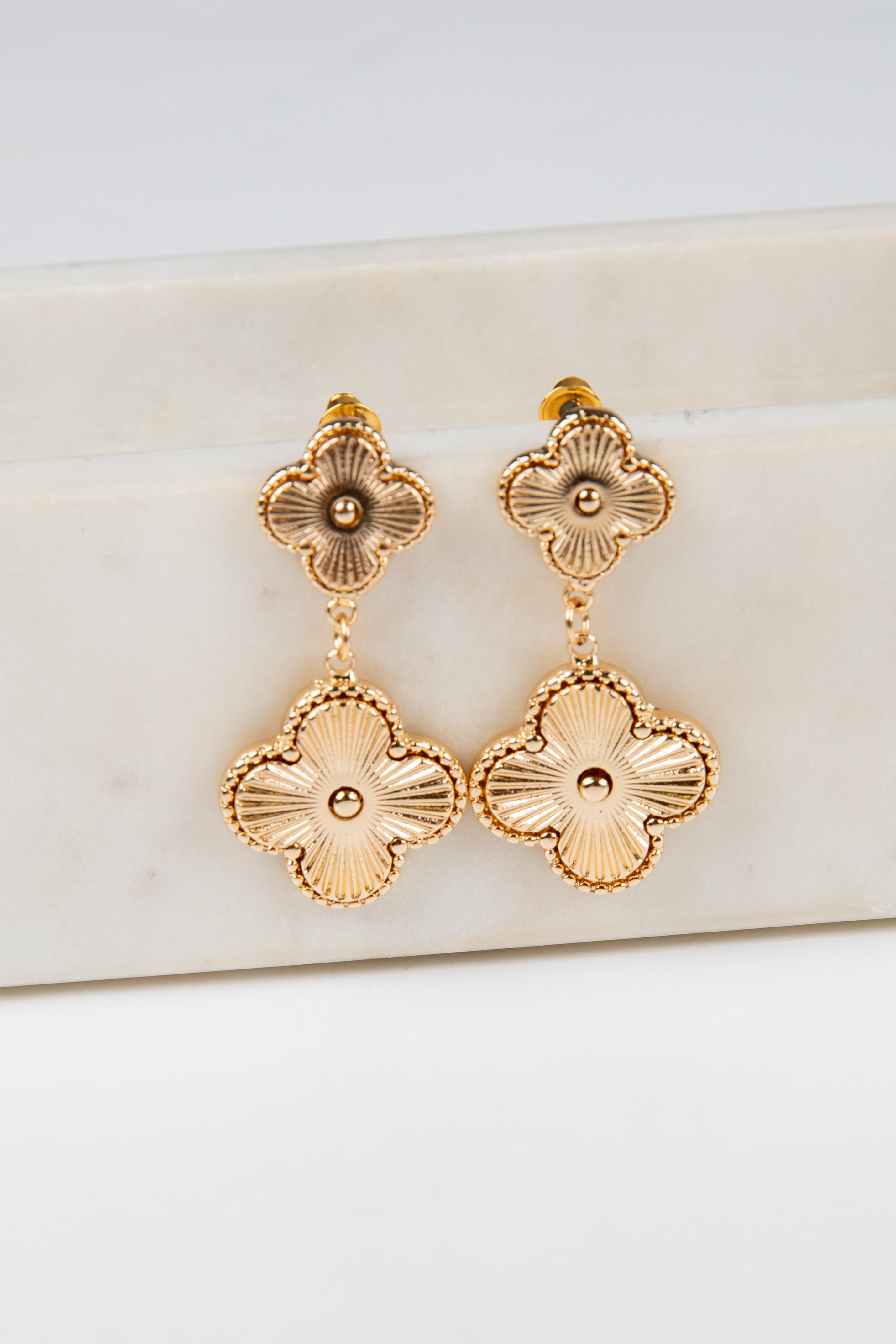 Gold floral earrings on a white background