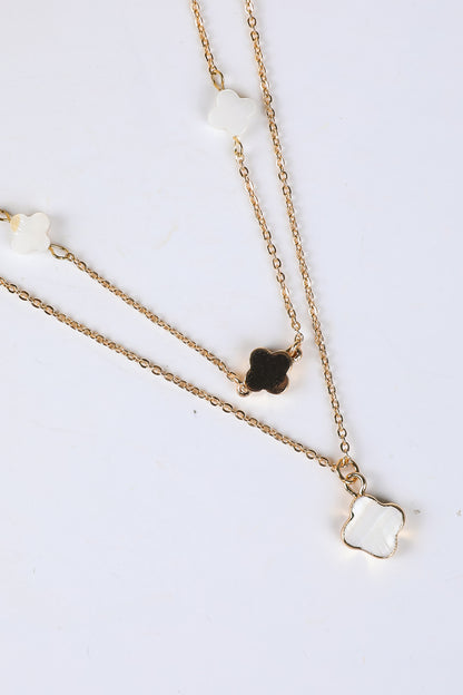 Two gold necklaces with clover pendants on a white background