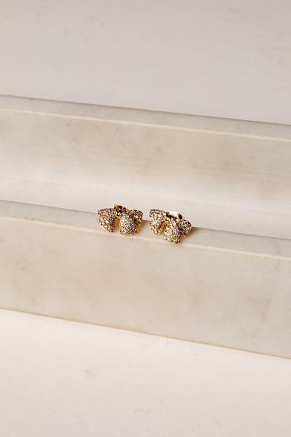 Gold earrings on a white surface