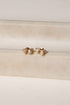 Gold earrings with clear stones on a beige fabric background