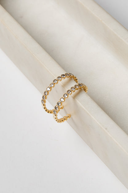 Gold earrings with embedded stones on a white surface