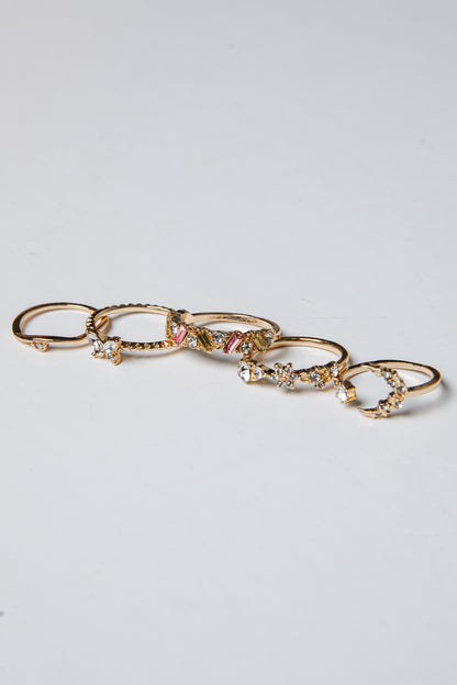 Set of gold rings with gemstones on a light gray background