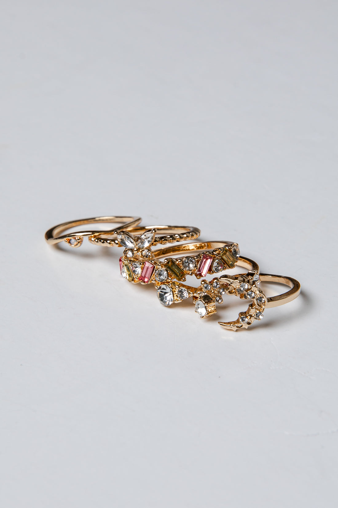 Gold rings with gemstones on a light gray background