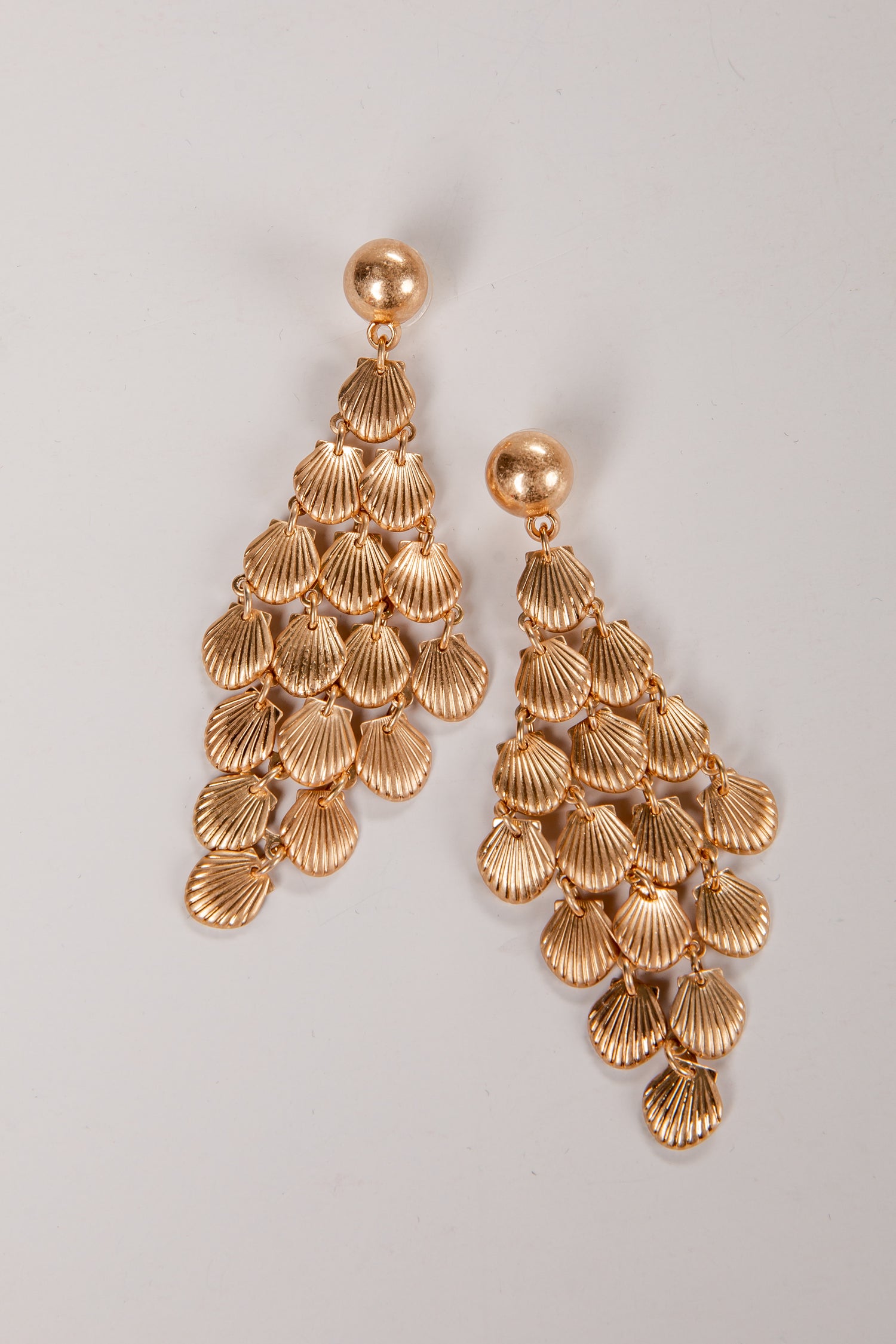 Gold shell-shaped earrings on a light gray background
