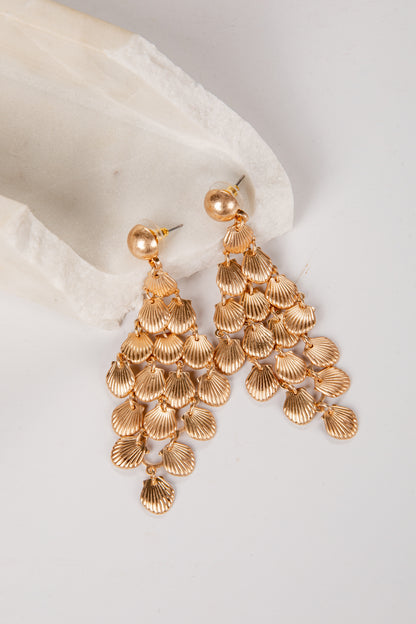 Gold chandelier earrings on a white fabric background