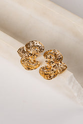 Gold earrings on a white fabric background