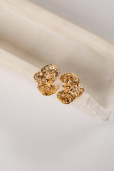 Gold floral earrings on a white fabric background