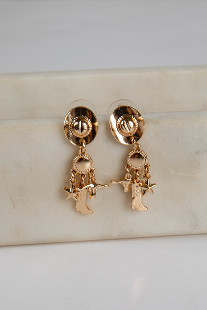 Gold earrings with character charms on a light background