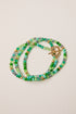Multistrand beaded bracelet with a gold clasp on a beige background
