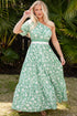 Woman in a green floral dress standing in front of palm leaves