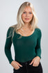Woman wearing a green long-sleeve top against a gray background