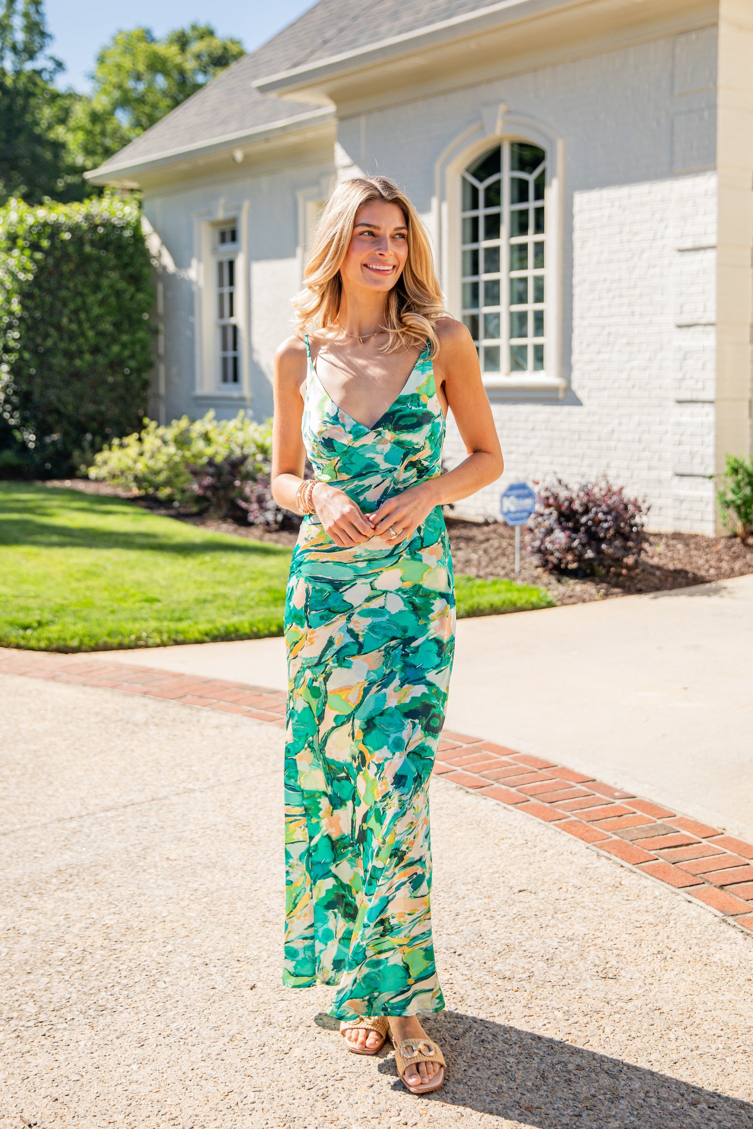 Woman in a floral dress standing on a driveway with a house in the background