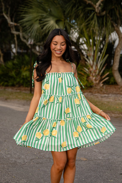 Woman wearing a green and white striped dress with yellow pineapple patterns outdoors.
