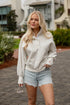 Woman wearing a light gray sweatshirt and denim shorts outdoors.