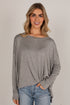 A woman wearing a heather gray long-sleeve knit top with a wide boat neckline and a relaxed, slightly oversized fit, paired with blue jeans against a plain light gray studio background.