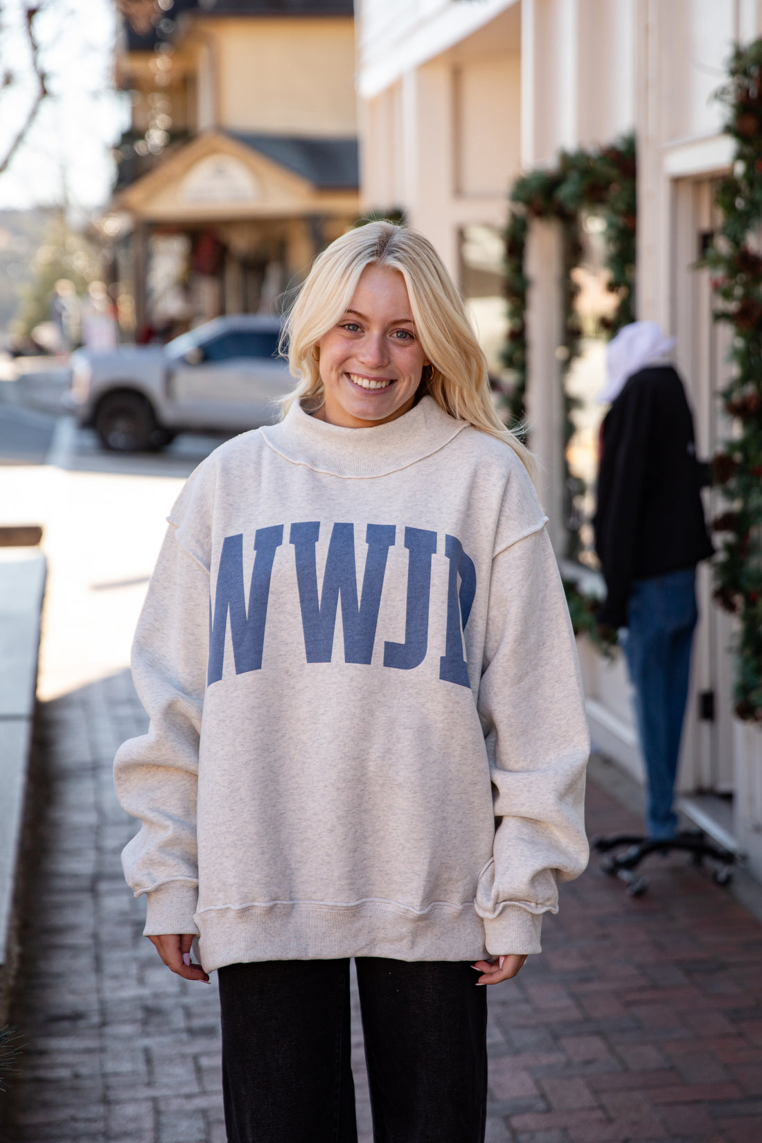 Person wearing a beige sweatshirt with &