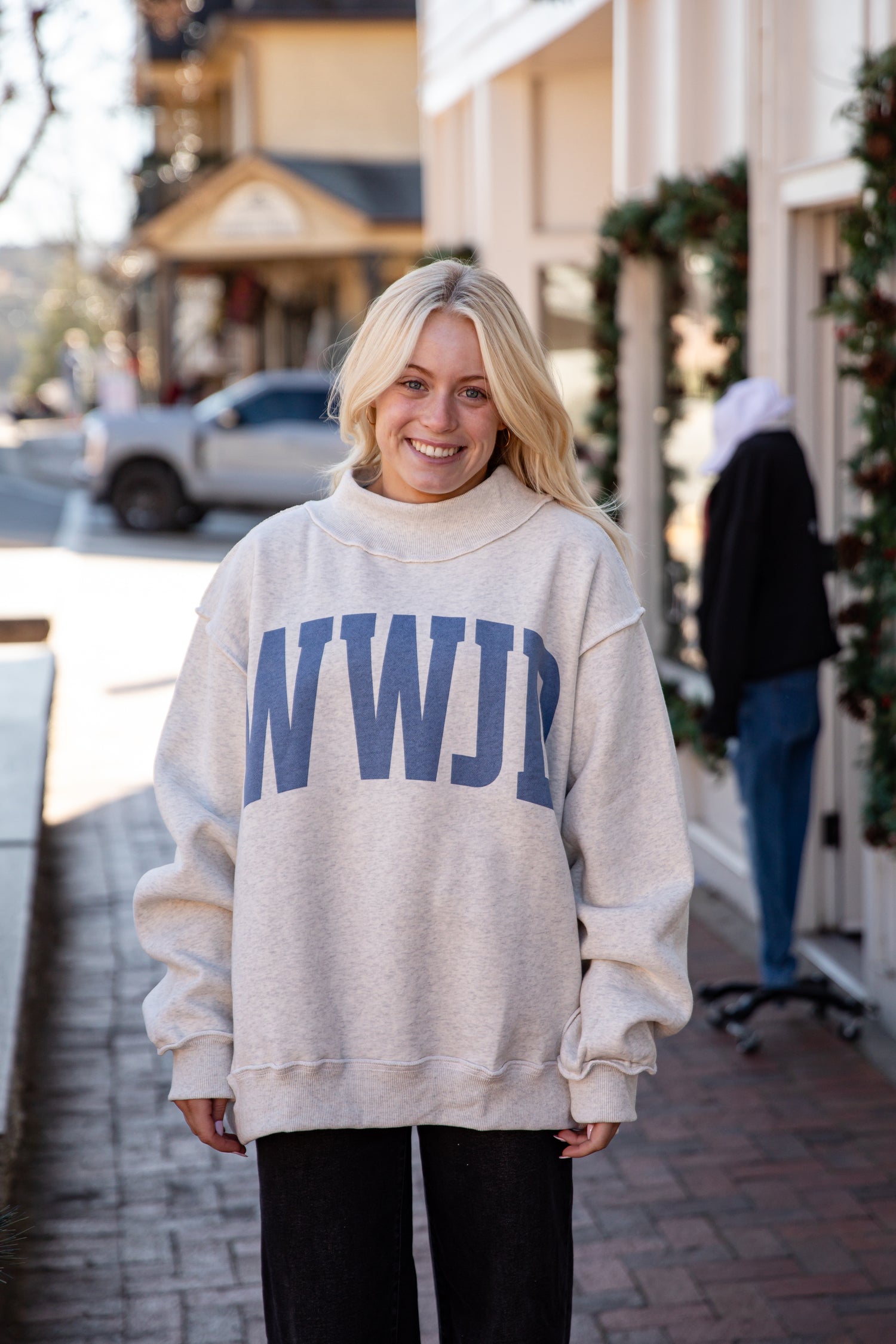 Person wearing a beige sweatshirt with &