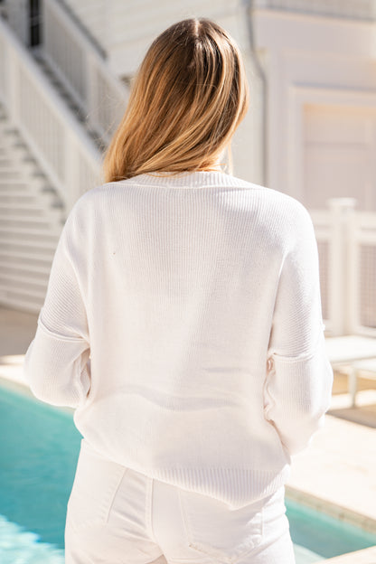 Person wearing a white outfit by a poolside with a neutral background