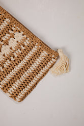 Brown and beige woven clutch bag with a tassel on a light background
