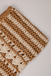 Close-up of a brown and beige crocheted fabric on a light background