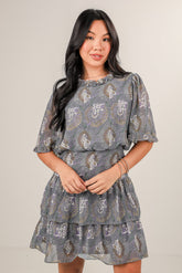 Woman wearing a patterned dress against a plain background