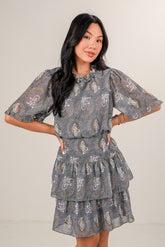 Woman wearing a gray patterned dress against a plain background