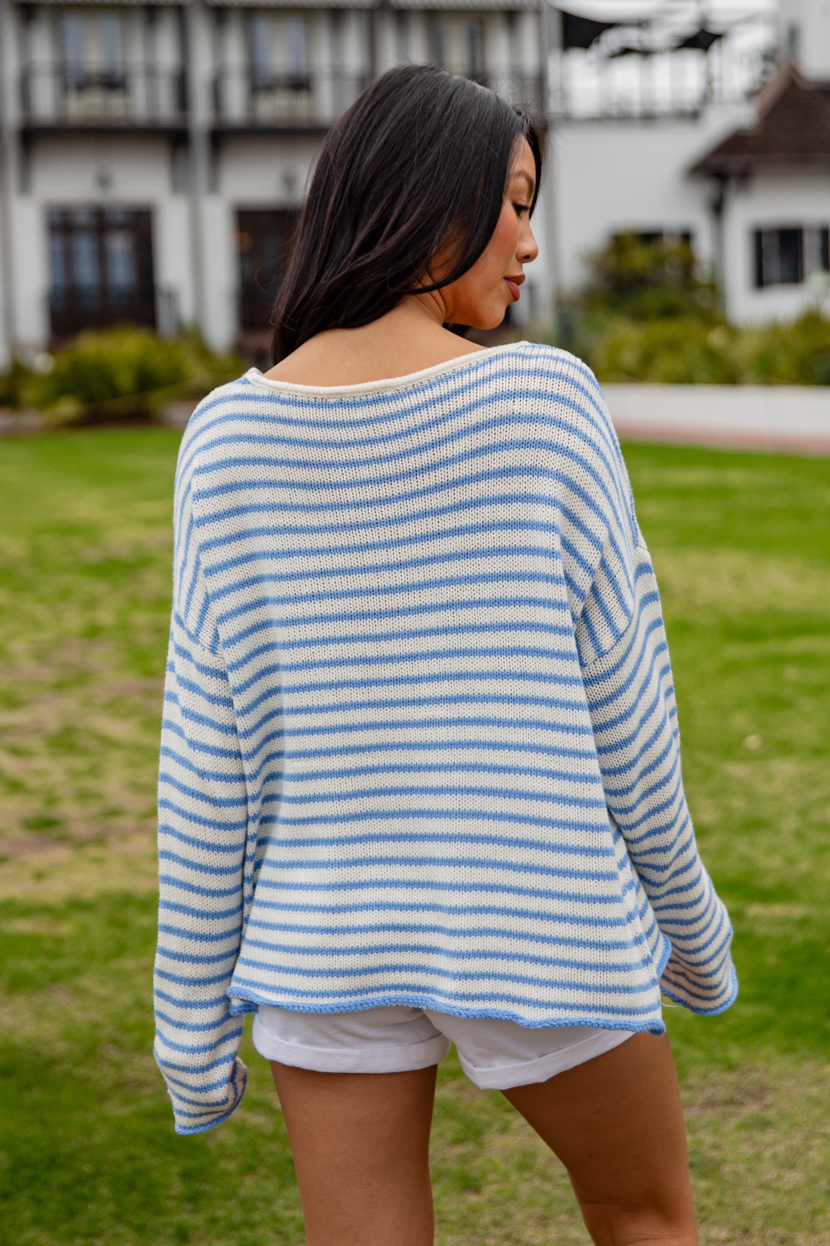 Woman wearing a blue and white striped sweater and shorts in an outdoor setting.