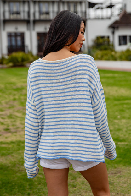 Woman wearing a blue and white striped sweater and shorts in an outdoor setting.