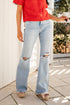 Person wearing red sweater and light blue ripped jeans standing on a tiled floor.