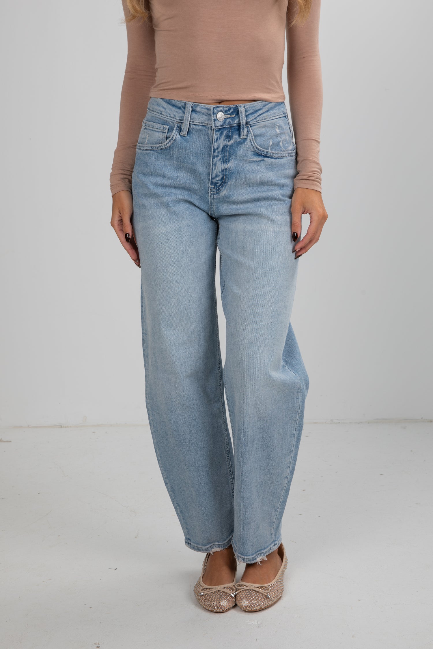 Person wearing light blue jeans and a beige top on a white background