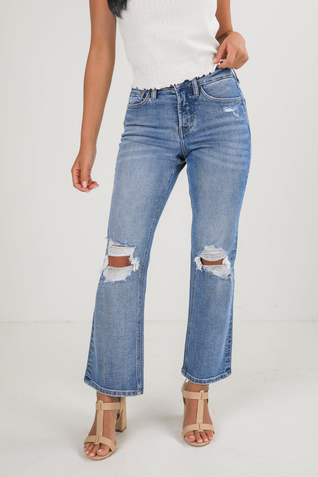 Person wearing distressed blue jeans on a white background