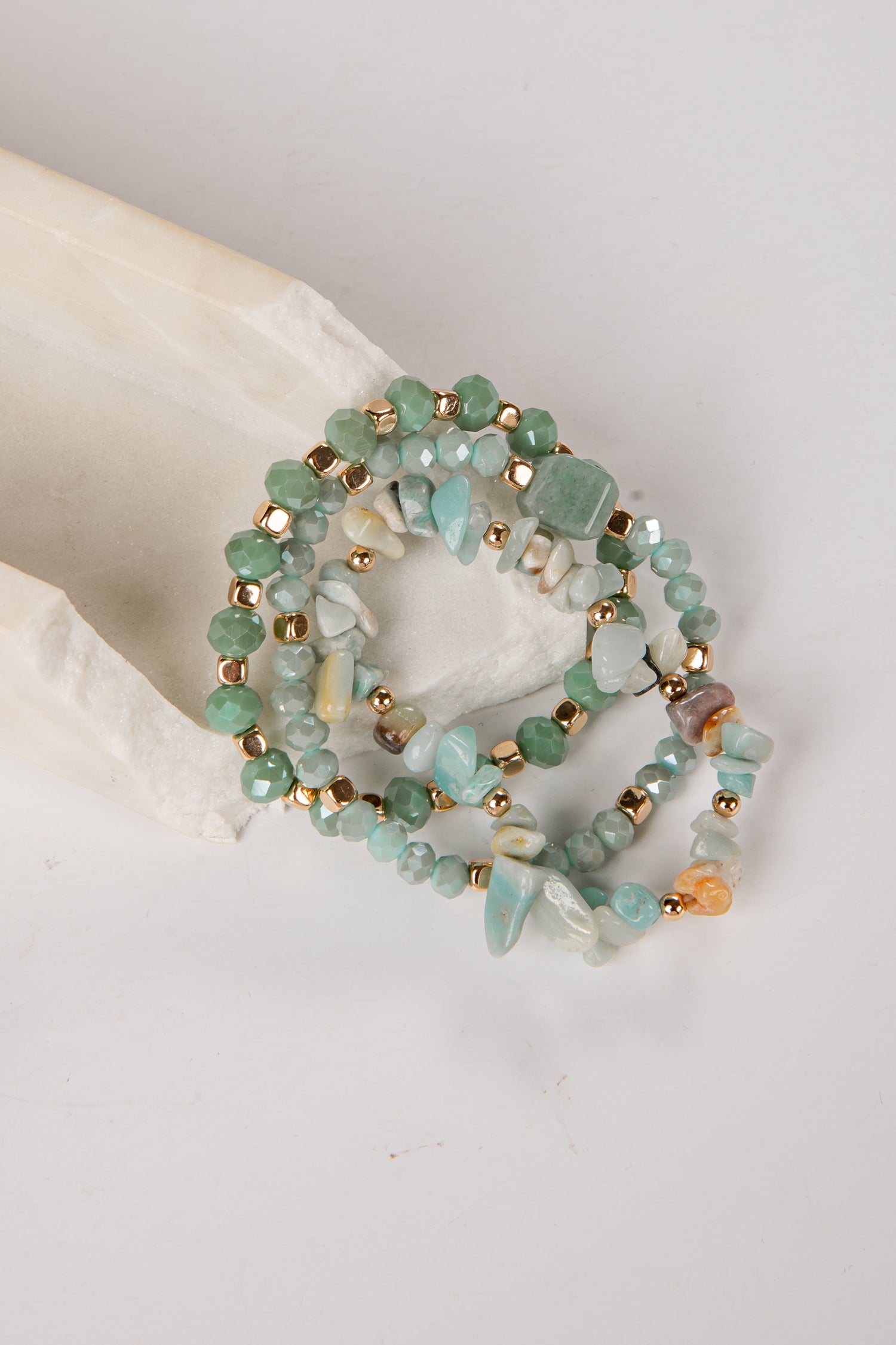 Set of three beaded bracelets with gold accents on a light background