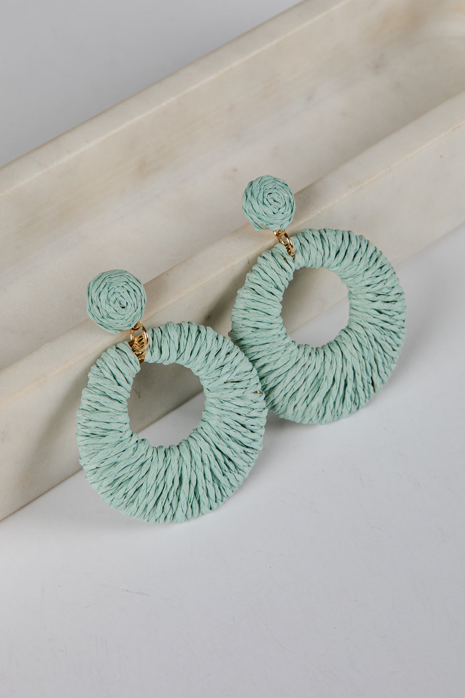 Pair of light blue textured hoop earrings on a light background
