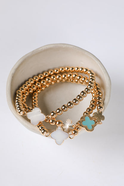 Gold bracelets with charms on a white background