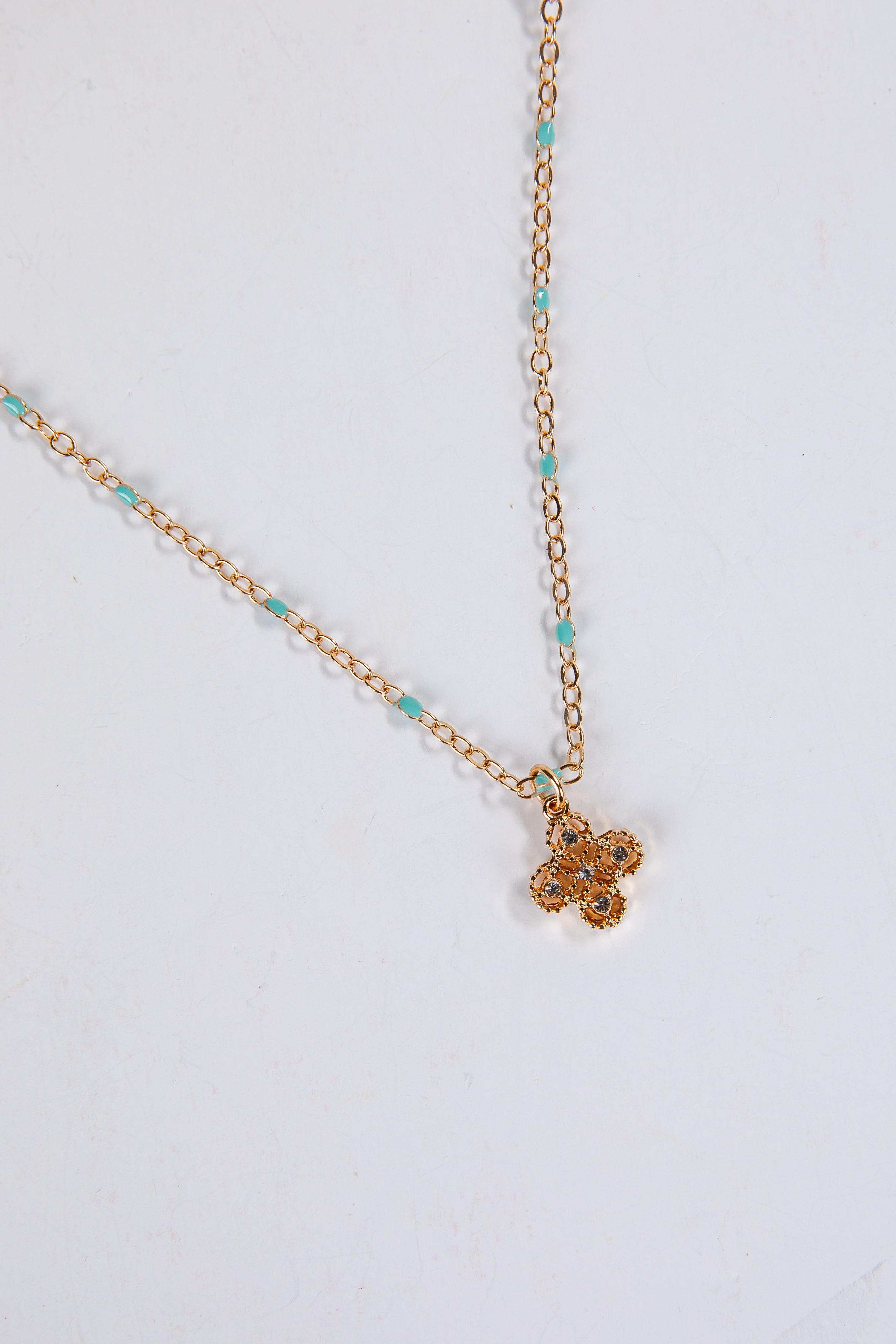 Gold necklace with a small pendant on a light gray background