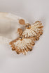 Pair of gold and white earrings on a light fabric background