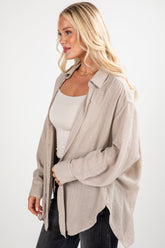 Woman wearing a beige cardigan over a white top and black pants on a white background