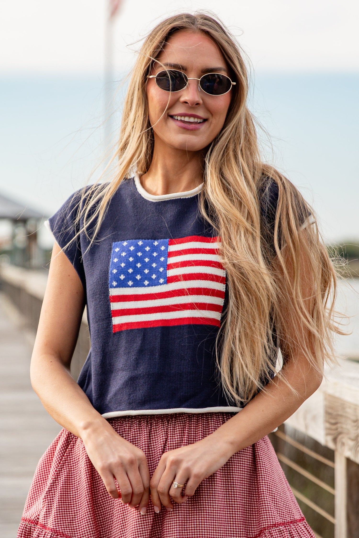 Woman wearing a navy blue t-shirt with an American flag design, standing on a wooden dock.