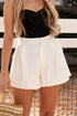 Person wearing a black top and white shorts with a blurred background