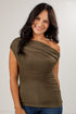 A woman with long dark hair wearing a ribbed olive green one-shoulder top and blue jeans, posing against a light gray studio background.