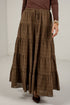 A brown tiered maxi skirt with a subtle plaid pattern, worn by a model with a brown long-sleeve top and dark brown pointed-toe heels.