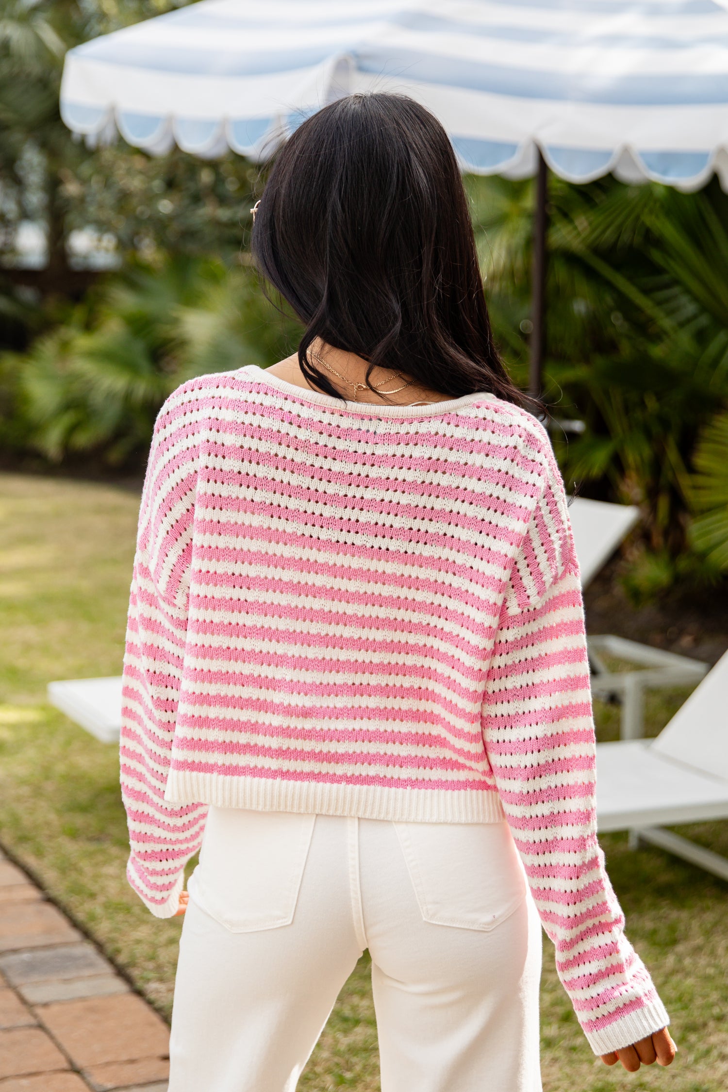 Person wearing a pink and white striped sweater in an outdoor setting