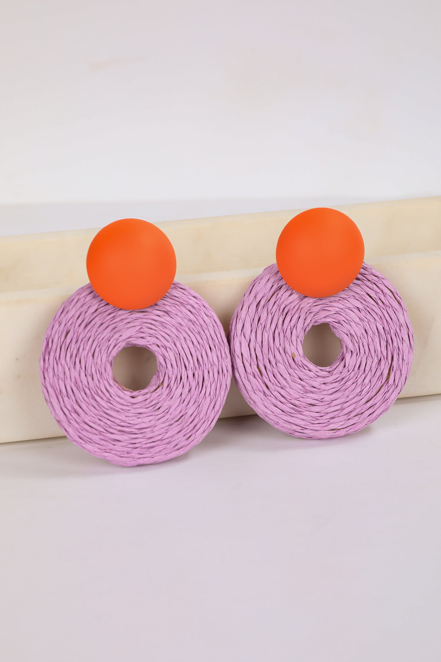 Pink earrings with orange tops on a white background