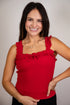 Woman wearing a red sleeveless top with ruffled details against a plain background