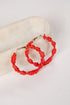 Red hoop earrings on a mannequin arm against a white background