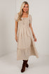 A woman modeling a beige and white gingham midi dress with puff sleeves, a smocked bodice, and a tiered skirt, paired with brown suede boots against a white studio background.