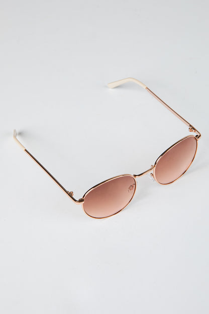Rose gold sunglasses with pink lenses on a light gray background